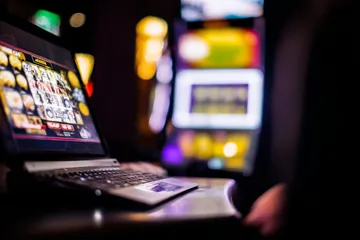 Une femme sourit près de machines à sous lumineuses affichant des symboles chanceux, mettant en valeur l'offre de slots BOOMERANG.